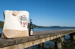 Ein Steg, auf dem eine Tasche und eine Flasche mit dem Fischerei Tegernsee Logo stehen. Im Hintergrund sieht man den See.